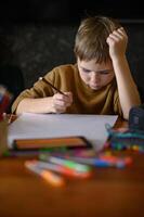 The boy holds a marker, pausing to decide what to create on the paper. photo
