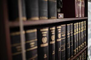 A close-up of a bookshelf showcasing jurisprudence books in Greek, with a striking bust of Alexander the Great in the center photo