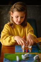 In a warm room, a girl leans over the table, enjoying a board game. photo