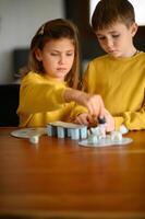 The siblings challenge each other in a friendly game, sitting at the table at home photo