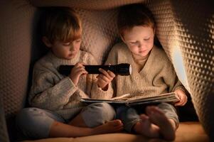 A heartwarming scene of two brothers reading together under a blanket with a flashlight. photo