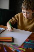 A young boy, with markers in hand, thinks deeply about his next drawing idea. photo