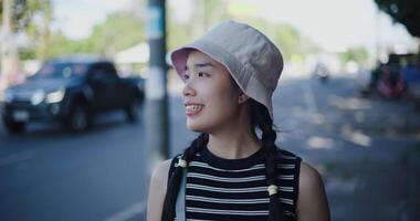 Happy Asian woman enjoys a leisurely stroll on an outdoor sidewalk and looks at the surrounding scenery. video