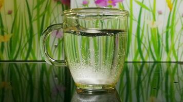 mug of water in which an effervescent aspirin tablet dissolves, slow motion video