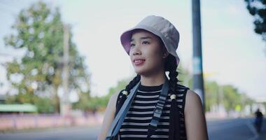 Handheld shot, Beautiful Asian woman in casual clothes is having fun taking photos of the city view with a camera on a sidewalk in the city video