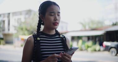 Handheld shot, Young Asian woman standing outdoors enjoying the view of the city while using a map app to find directions on mobile phone video