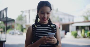Young Asian woman standing outdoor enjoying the view of the city while using a map app to find directions on mobile phone. video