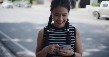 Young Asian woman standing outdoors enjoying the view of the city while using a map app to find directions on mobile phone. video