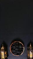 A Plate of Dates between Two Lanterns Decoration on Black Background photo