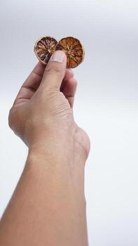 Hand Showing Two Slices Dried Lemon on White Background photo