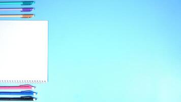 Various Color of Pens and Notebook on Blue Background photo