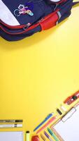 Backpack, School Stationery, and Wooden Clip Board with Copy Space Area in the middle on Yellow Background photo