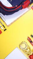 School Stationery, Notebook, Backpack, and Wooden Clip Board with Copy Space Area on Yellow Background photo