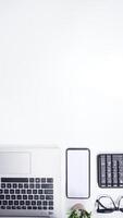 Top View of Workspace with Laptop, Keyboard, Mobile Phone on White Background photo