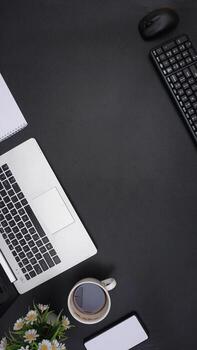 Top View of Laptop, Keyboard, Mouse, Coffee Cup, and Mobile Phone on Dark Background photo