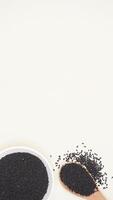 Black Cumin Spice on Plate and Wooden Spoon on Light Background photo