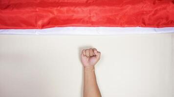 Indonesia Red and White Flag with Man's Fist on Light Background photo