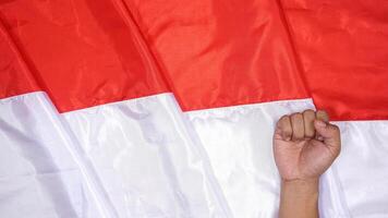 Red and White National Flag of Indonesia as Background for Copy Space with Man's Fist photo