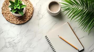 Notebook, pen, and plant on marble table photo