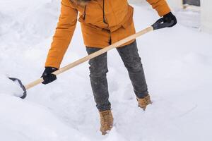 Man cleaning snow from sidewalk and using snow shovel. Winter season photo