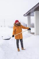 Man is clearing the snow near house and on staircases hovelling at the winter season. Winter storm and season specific photo