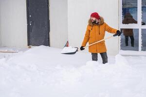 A man cleans and clears the snow in front of the house on frosty day. Cleaning the street from snow on a winter day. Snowfall and severe snowstorm in winter. photo