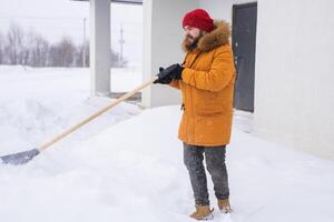 Man removing snow and ice from the sidewalk in front of house. Winter season photo
