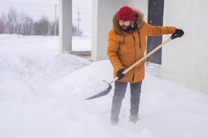 Man removing snow and ice from the sidewalk in front of house. Winter season photo