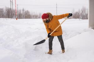 A man cleans and clears the snow in front of the house on frosty day. Cleaning the street from snow on a winter day. Snowfall and severe snowstorm in winter. photo