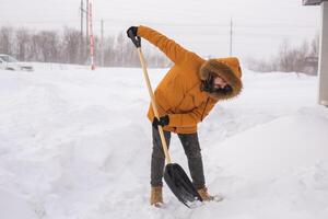 Man removing snow and ice from the sidewalk in front of house. Winter season photo