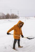 A man cleans and clears the snow in front of the house on frosty day. Cleaning the street from snow on a winter day. Snowfall and severe snowstorm in winter. photo