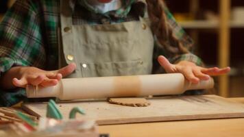 Talented creative teenage Caucasian little girl artist sculptor child ceramist kid student use wooden rolling pin rolls clay material preparing craft artwork sculpture ceramic pottery indoor workshop video