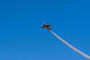 A small plane flying through the sky with smoke trailing behind it photo