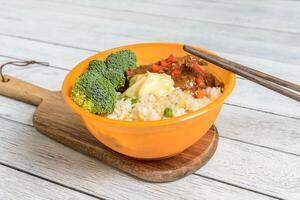 A bowl of food with chopsticks and broccoli photo