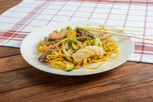 A plate of noodles and meat on a table photo