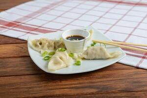 A plate with dumplings and sauce on a wooden table photo