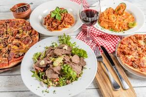 A table with several plates of food and a glass of wine photo