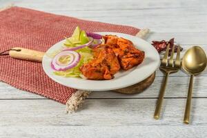 A plate with chicken, onions and salad on a red cloth photo