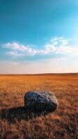 A large rock sits in the middle of an open field photo