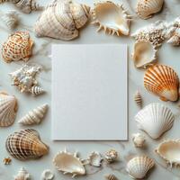 Creative workspace with blank paper surrounded by various seashells on marble surface photo