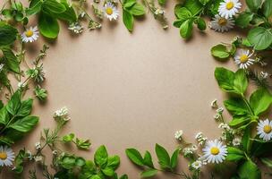 Natural frame of green leaves and white flowers arranged on a beige background for creative projects photo