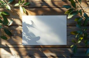 Blank card placed on rustic wooden surface surrounded by green leaves and soft shadows in natural light photo
