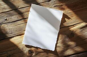 Blank sheet of paper resting on rustic wooden table with shadows from overhead light photo