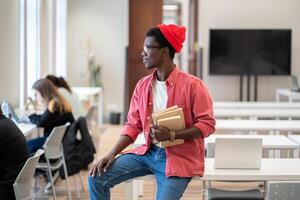 Black student guy looking out of window thinking about weekend plans while studying in library photo