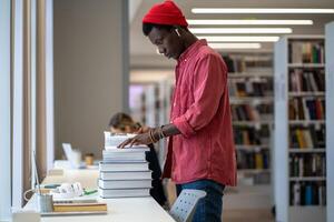 African American student guy standing in library looking for dissertation resources photo