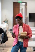 Black student man chatting in social media on smartphone while studying in university library photo