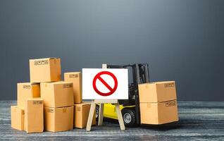 Warehouse with boxes and forklift and easel with prohibition sign NO. Out of stock. Restrictions ban on import goods. Sanctions, trade wars. Isolation and quarantine. manufacturers production slowdown photo