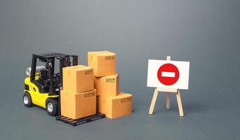 Forklift with boxes and an easel with restriction sign. Restrictions on export of scarce and medical goods for period of border closure quarantine pandemic. Self-isolation, obstacle to globalization photo