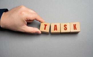 Task word concept. Business tasks and goal setting. Strategy and business management. Businessman holding wooden blocks photo