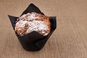 Muffin in a paper cup on a burlap background . . photo